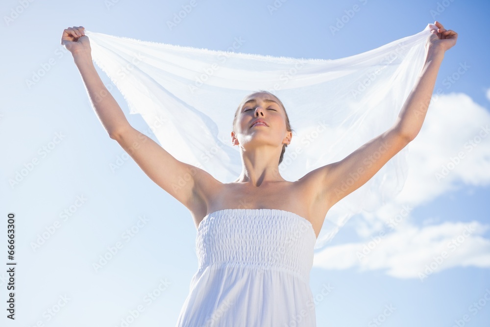 Pretty blonde in white dress holding up shawl on the beach Pretty blonde in white dress holding up shawl on the beach