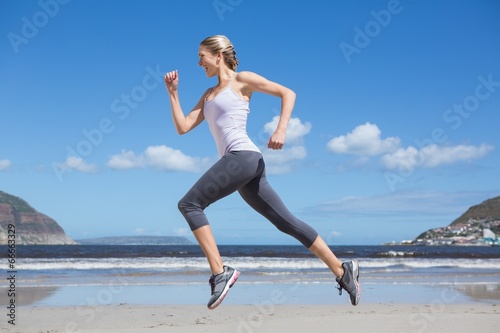 Fototapeta Naklejka Na Ścianę i Meble - Pretty fit blonde jogging on the beach