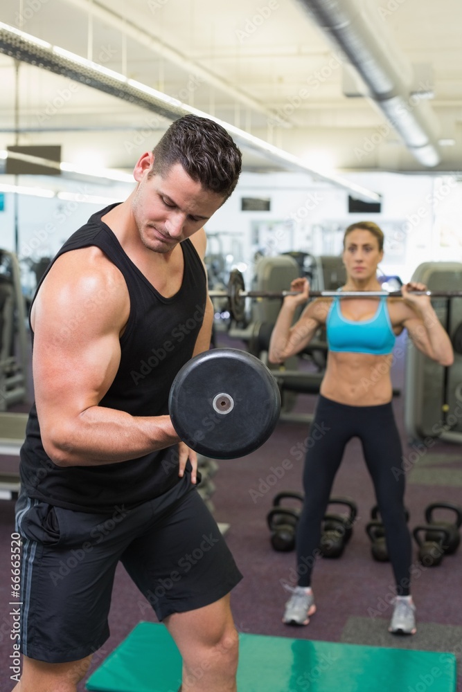 Muscular man and woman lifting weights Muscular man and woman lifting weights