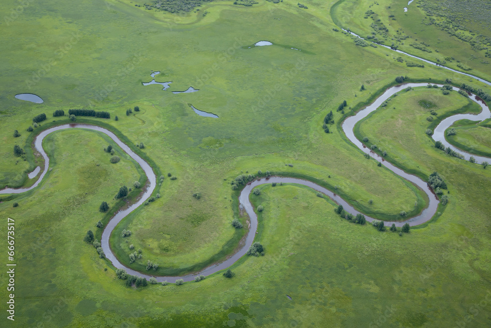 aerial view over the small river on the green grassland aerial view over the small river on the green grassland
