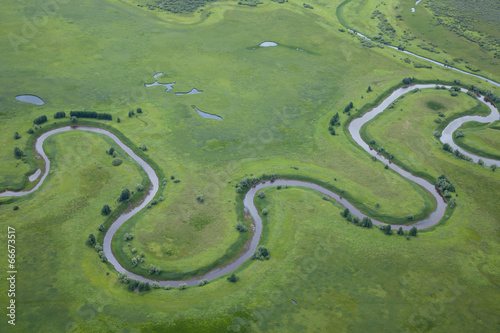 aerial view over the small river on the green grassland