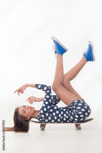 Teenage girl in dress on skateboard
