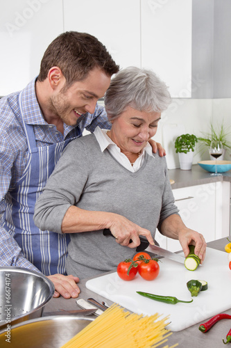 Young man and older woman cooking together in the kitchen.