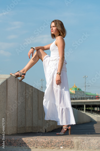 Beautiful girl in white dress strolls along the river