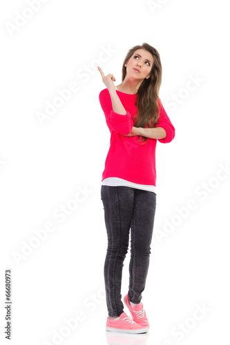 Young woman pointing up at empty space. © studioloco