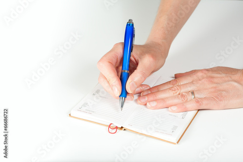 Mani di donna scrivono su agendina in pelle photo