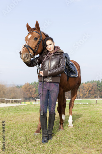 equestrian with her horse on meadow