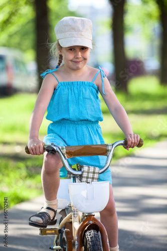 Beautiful girl in blue dress riding bicycle