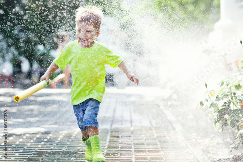 Playful boy runing on rainy summer day 