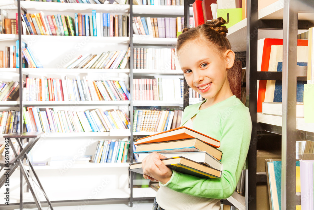 Schoolgirl smiles and holds books in library Schoolgirl smiles and holds books in library