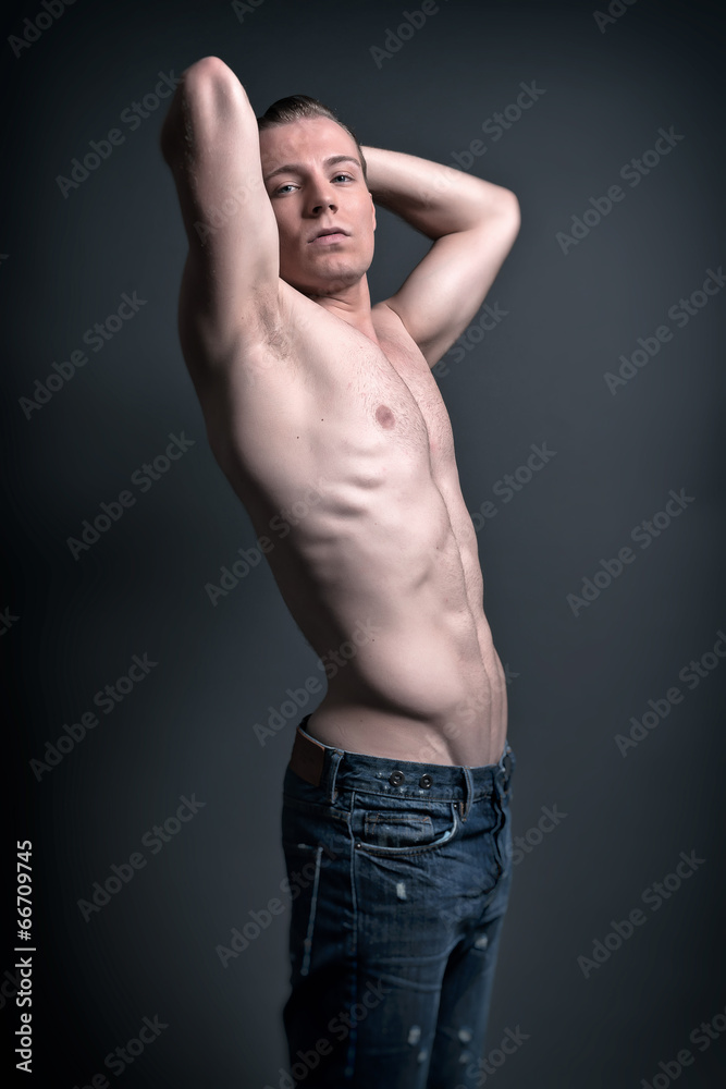 Fototapeta premium Healthy good looking young muscled fitness man wearing blue jean