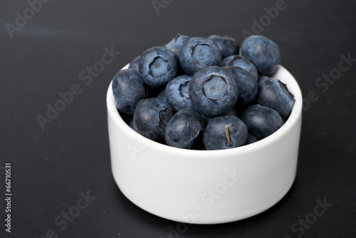 white bowl with blueberries on a black background  close-up