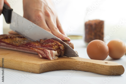 Woman's hands cutting bacon into strips, close up