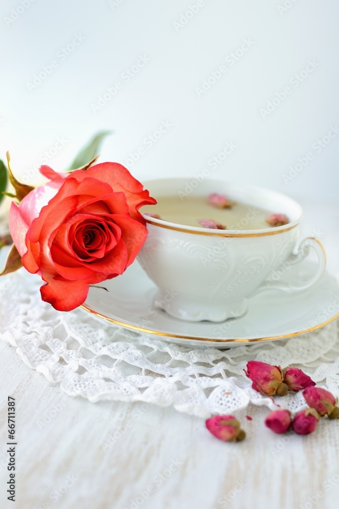Cup of tea with dried roses and fresh rose