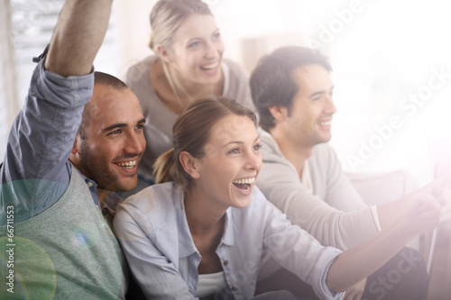 Cheerful group of friends watching football game on tv