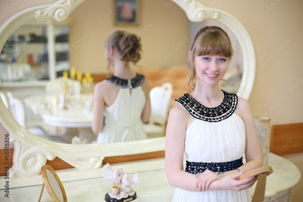 Beautiful smiling girl stands near mirror and holds frame