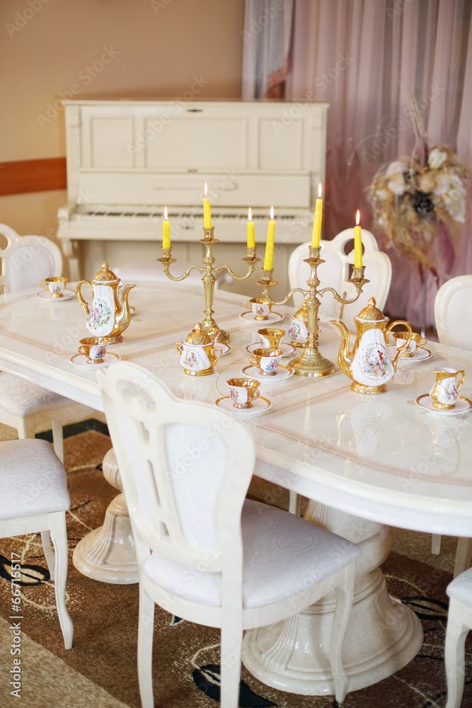 Table with set of porcelain dishes and lighted candles