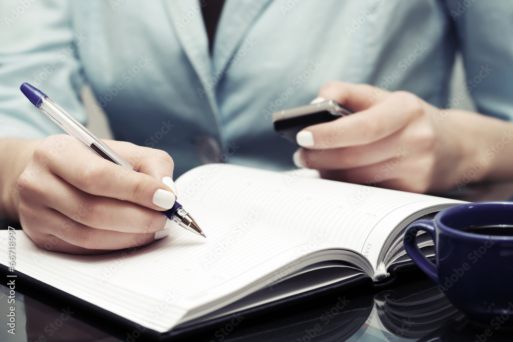 Business woman writing in notebook