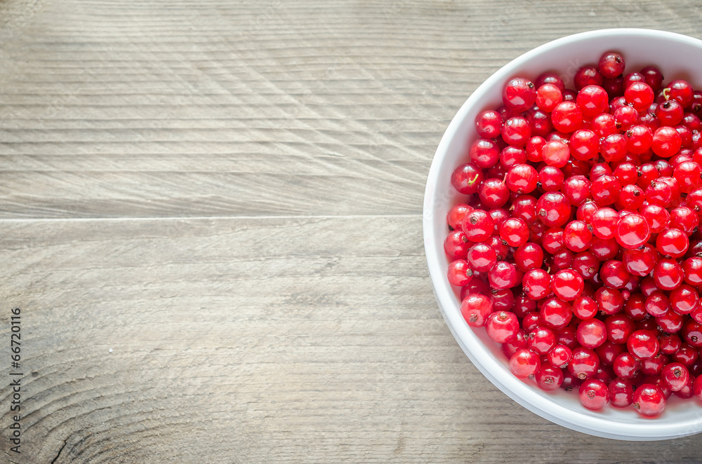 Bowl with fresh redcurrant on the wooden table Bowl with fresh redcurrant on the wooden table