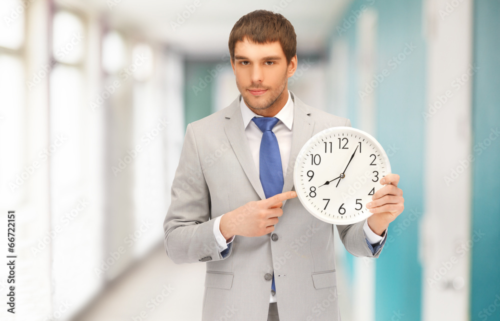 handsome businessman pointing finger to wall clock handsome businessman pointing finger to wall clock