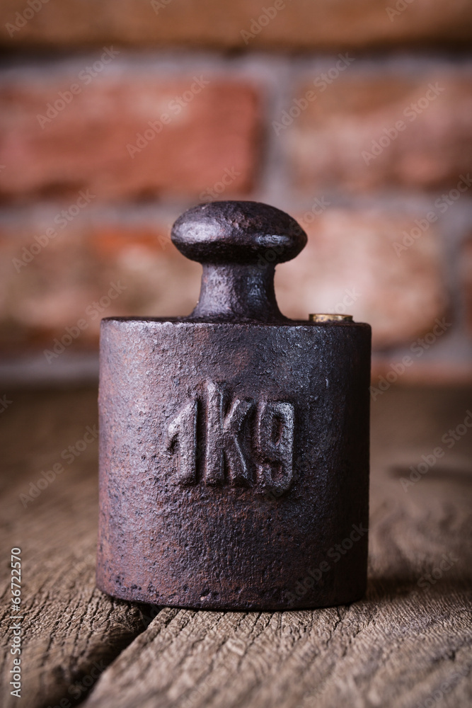 Vintage iron 1 kg weight in front of an old brick wall.