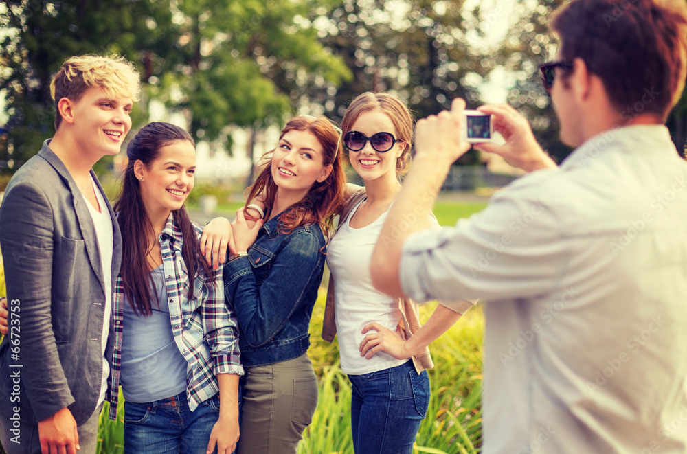 teenagers taking photo with digital camera outside