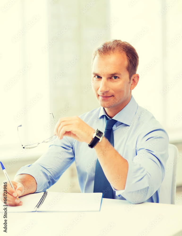 businessman with spectacles writing in notebook