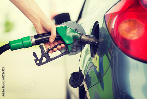 man pumping gasoline fuel in car at gas station photo