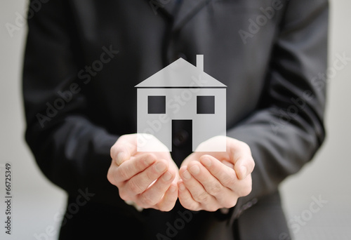 hands of a man holding a house, insurance and protection concept