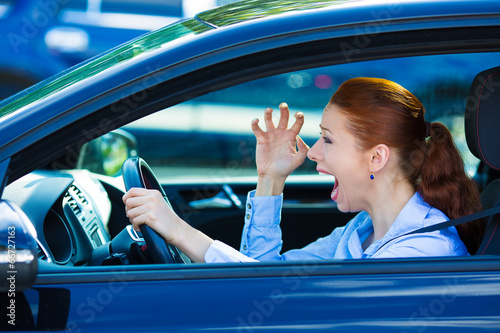 Angry young female driver, frustrated screaming while driving  photo