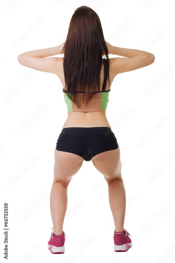 Young girl in short shorts and a sports shirt performs squats. Stock Photo