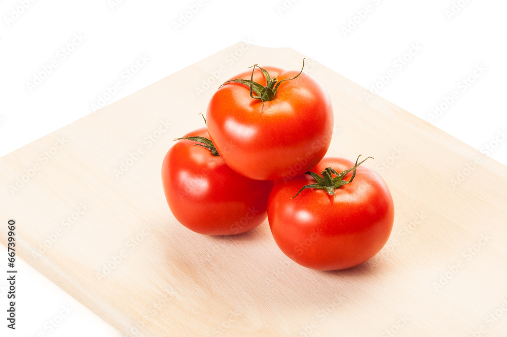 Three red tomatoes arranged on wooden board. Three red tomatoes arranged on wooden board.