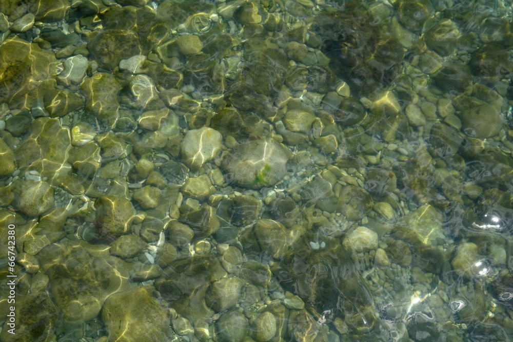 Obraz premium Ripples creating shadows onto round pebbles in water