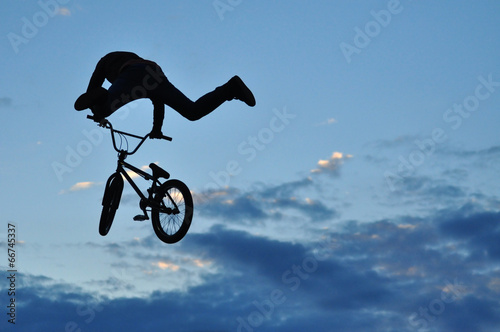 Silhouette of a BMX rider making a bike jump in the air
