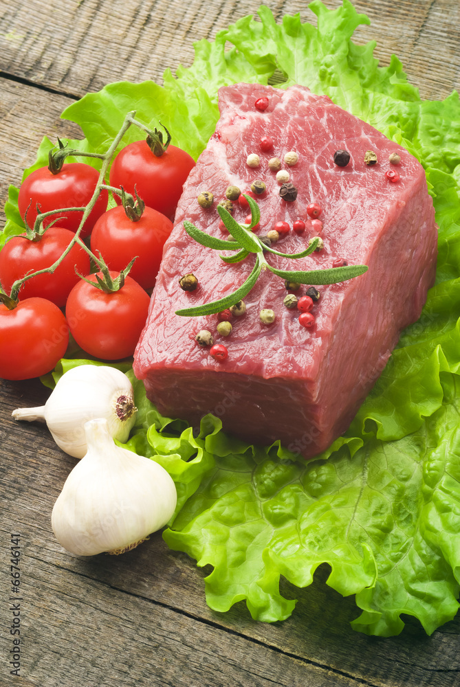 Raw Steak with green lettuce on wooden board Raw Steak with green lettuce on wooden board