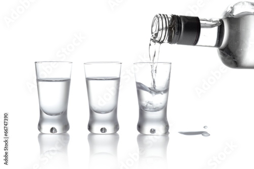 Photo Bottle and glasses of vodka poured into a glass isolated on whit