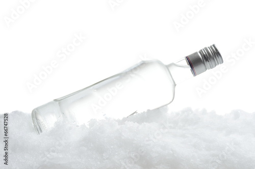 Bottle of vodka lying on ice on white background