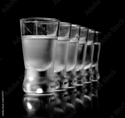 Photography Many glasses of vodka isolated on black background