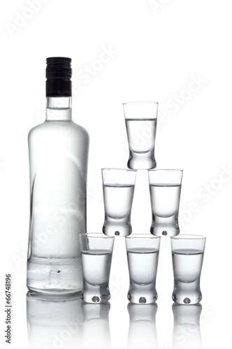 Bottle with many glasses of vodka isolated on white background