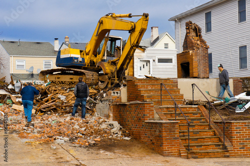 A large backhoe demolishes an old building