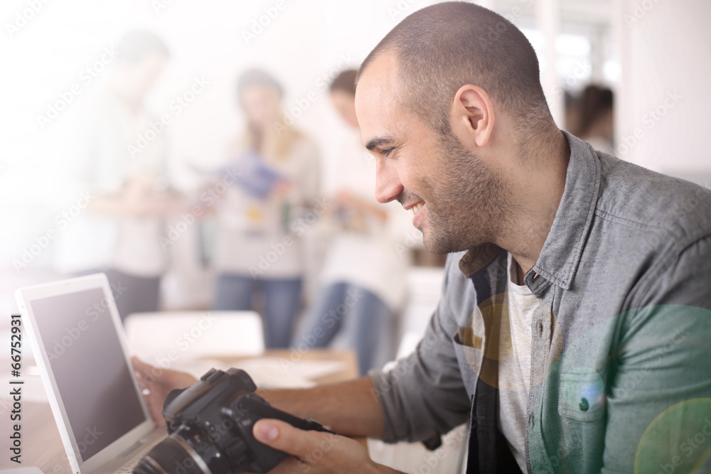 Cheerful reporter working in office on laptop