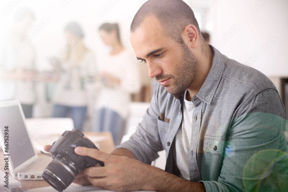 Fototapeta premium Cheerful reporter working in office on laptop