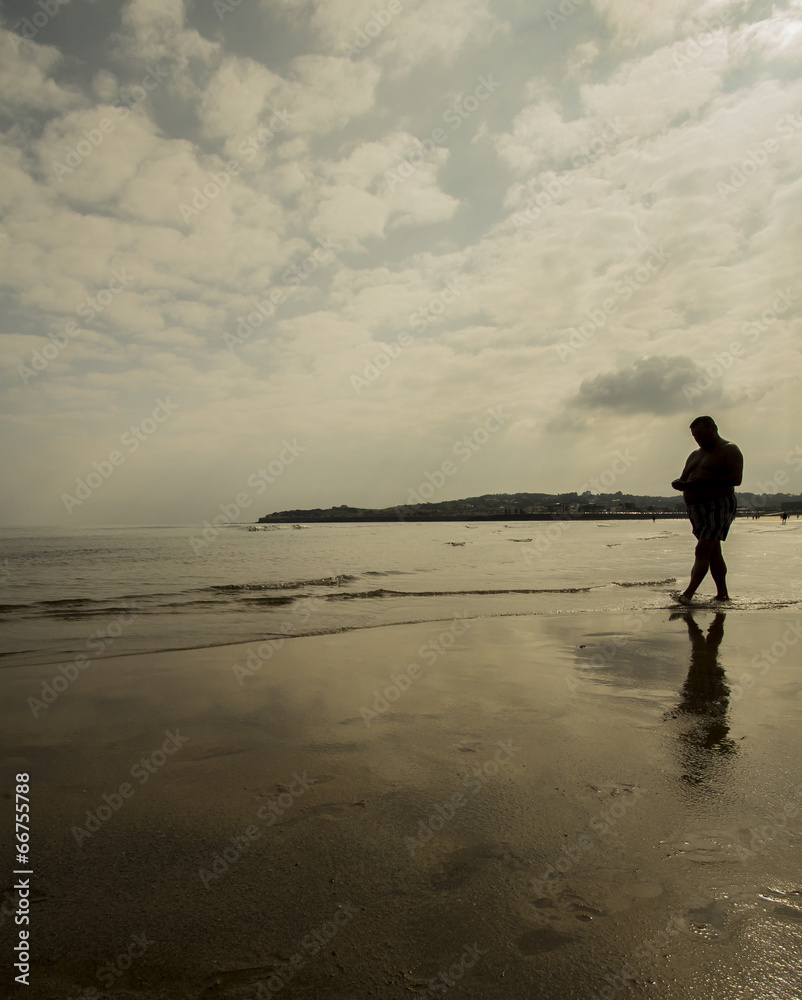 Naklejka premium Anciano paseando por la playa
