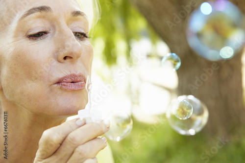 Senior woman blowing bubbles outdoors