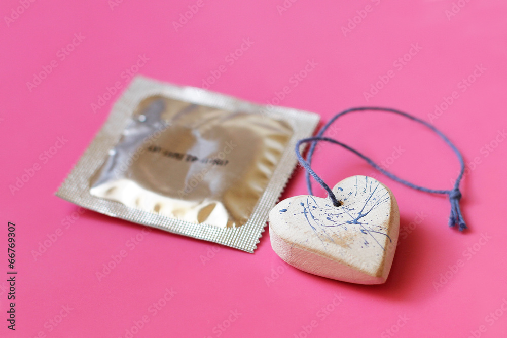 Heart and a condom on pink background