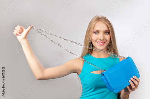 Красивая блондинка с синей сумочкой в рукх