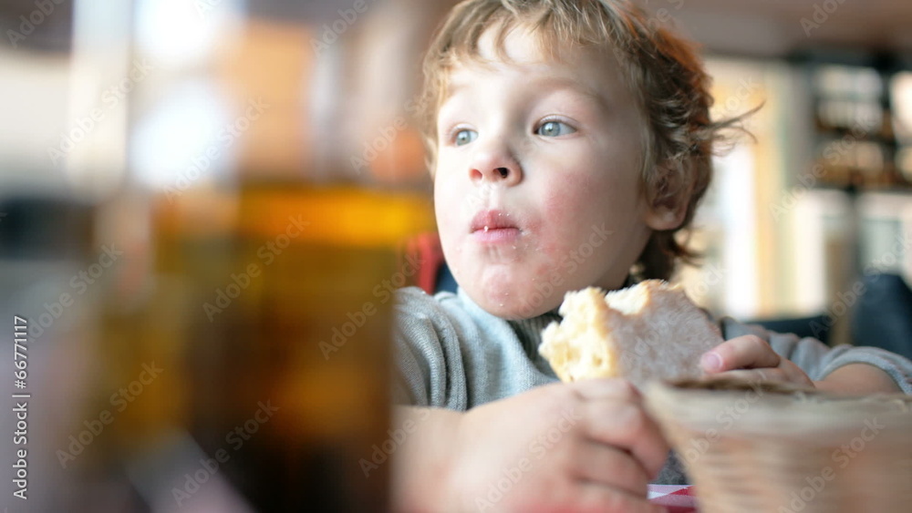 Cute boy eating a bun in a cafe Cute boy eating a bun in a cafe
