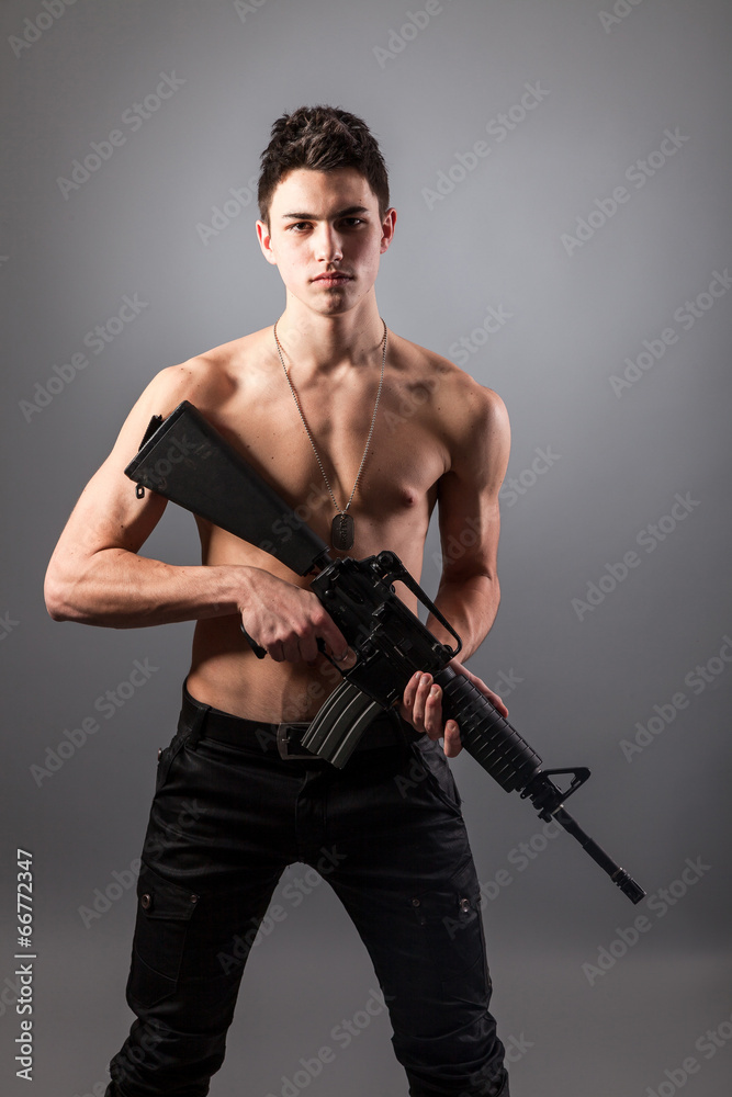 Handsome bare-chested soldier is holding a rifle Handsome bare-chested soldier is holding a rifle