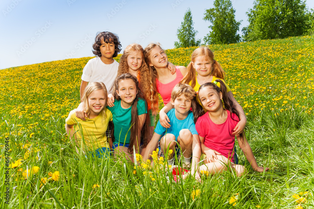 Eight kids sitting together on the green grass Eight kids sitting together on the green grass