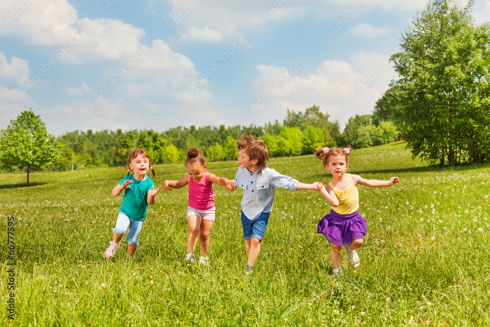 Four kids holding hands and standing together